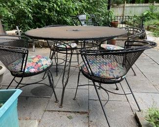 1960'S MID CENTURY MODERN METAL MESH SALTERINI PATIO SET WITH FOUR CURVED BARREL BACK CHAIRS, ANGLED LEGS AND SLOPING SEAT, TABLE HAS HOLE FOR UMBRELLA. HIGHLY COLLECTIBLE!