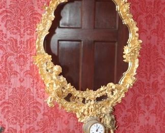 19th c. Louis XV style carved Giltwood Hall Mirror with a putti dragging a garland and a Marble and Gilt Mantle Clock