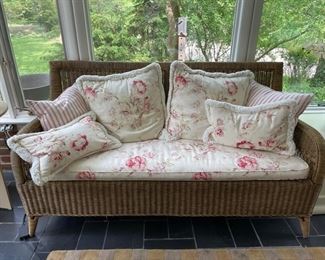 Crate & Barrel Wicker Loveseat with floral upholstered seat cushions and accent pillows.
