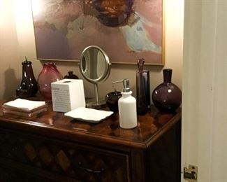 The bathroom holds many treasures including this three drawer chest and plenty of art!