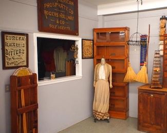 Victorian dress, stacked bookcase, advertising signs, brooms, bag rack, etc