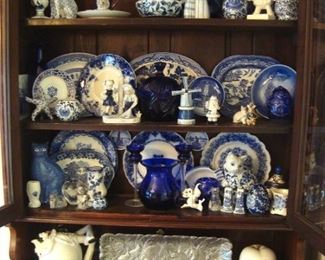 Antique china cupboard opened showing much flow blue china and collectibles.