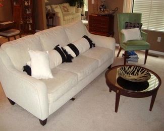 White sofa and round mirror top coffee table.