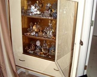 Vintage 1940's white cabinet loaded with crystal perfume bottles.