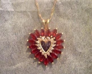 14 kt. gold heart shaped pendant with diamonds in center and 17 garnets on the outside on a 14 kt gold chain.