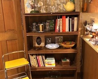 cookbooks, barrister bookcase pair, coffee cup tree, coffee cups, wine glasses, step stool,napkins in basket, wooden bowl with fruit decoration, vintage ice bucket and glasses in carrier, pear teapot,tall green glass vase with stopper, fly swatter, barometer