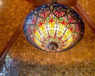 this stained glass fixture is approx. 4 feet in diameter. It’s up so high I can’t tell what the drop length is. 