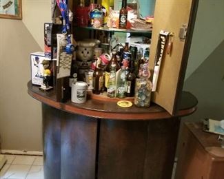 Art Deco bar with curved sides and glass shelves on top. Bottle storage below.