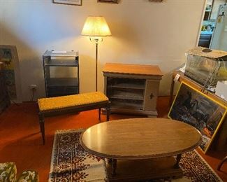 Multiple items shown: (Cherry oval coffee table is SOLD!), fabric covered piano table with flip up storage, one of multiple stereo cabinets with glass doors, approx. 48" tall 3-way floor lamp, TV stand with storage on the right side.