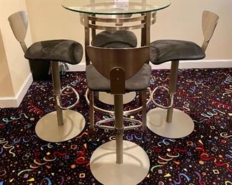 Lot 8009. $450.00 Glass top pub table with 4 metal frame and base, adjustable stools.  Black sueded microfibre.  The table is 30" Diameter and 42" T,  stools are adjustable Height.  This looks like out of a Star Wars Bar Scene!