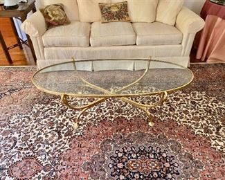 $395 - Brass and glass oval coffee table with brass duck supports - 15" H, 52" L, 22" W.