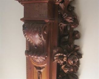 A pair of heavily carved wall columns with tiger heads and roses.