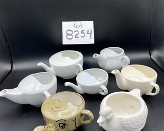 Lot 8254. $60.00 Lot of 8 side-handled infant/hospital/invalid feeders plus a cute duck shaped feeder that has a standard handle placement. 1) Gray, elephant snout feeder, 2) White duck with standard handle, 3) White, mini- side handle feeder, 4) cream colored - Royal Winton 'Made in England, 5) White, marked with an S under a crown made in Denmark, 6) white with a mark and #721, 7) marked #200 Schmid.