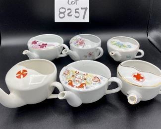 Lot 8257. $60.00. Lot of 6, side-handled infant/hospital/invalid feeders all with some design. 1) Red Cross, #4767 on bottom, 2) red, yellow & blue design and image of baby, 3) Red Cross/gold trim, marked "98" on bottom, 4) Pink & plum floral, marked "7317", 5) Purple floral with gold, 6) blue floral. Our favorite lot.
