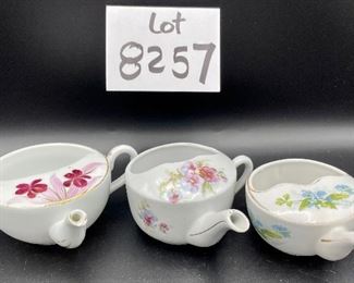 Lot 8257. $60.00. Lot of 6, side-handled infant/hospital/invalid feeders all with some design. 1) Red Cross, #4767 on bottom, 2) red, yellow & blue design and image of baby, 3) Red Cross/gold trim, marked "98" on bottom, 4) Pink & plum floral, marked "7317", 5) Purple floral with gold, 6) blue floral. Our favorite lot.