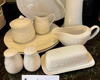 Lot 8295. $75.00. 10 pc. of White Fruits de blanc dinnerware serving pieces, featuring fruit decor in relief on all pieces, includes: 14" oval platter, covered butter dish, creamer, sugar, salt and pepper, gravy/saucer, 2 dinner plates or cookie plates, and a white Kaiser tankard or pitcher 9.5" T.