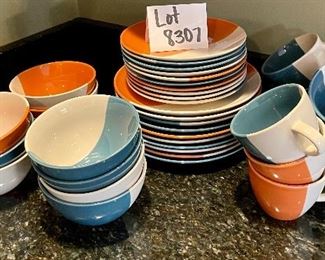 Lot 8307. $120.00 49 Pc ELITE by Gibson - dinnerware, dishwasher and microwave safe. 10 dinner plates, 10 salad plates 10 bowls and 9 mugs. Dishes are cream colored with either orange or teal accent color.