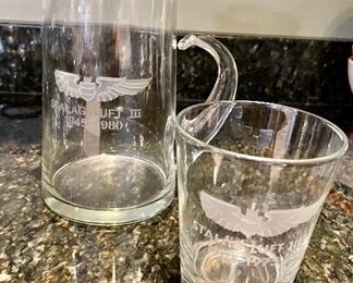 Lot 8323. $60.00 "Off we go into the Wild Blue Yonder...." a set of 8 silver rimmed Air Force Academy low-ball glasses and Stalag Luft pitcher with glass stirrer and a single low-ball glass.