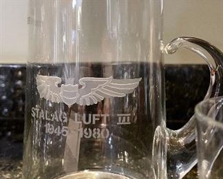 Lot 8323. $60.00 "Off we go into the Wild Blue Yonder...." a set of 8 silver rimmed Air Force Academy low-ball glasses and Stalag Luft pitcher with glass stirrer and a single low-ball glass.