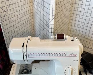 Lot 8359. $125.00 Janome portable sewing machine with travel case - Model 659- and 72" x 36" cardboard cutting grid.