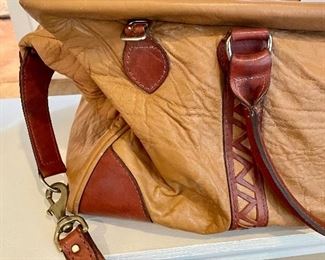 Lot 8370. $35.00 Leather structured duffle with reticulated cut leather accent design. Zipper closure with leather strap and handles. 24"L x 10"W 12" T