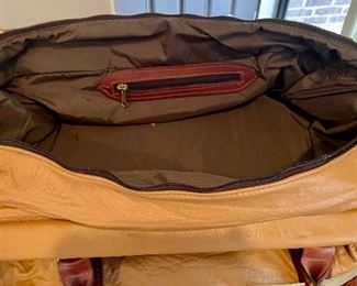 Lot 8370. $35.00 Leather structured duffle with reticulated cut leather accent design. Zipper closure with leather strap and handles. 24"L x 10"W 12" T