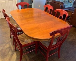 Lot 8238. $300.00 Beautiful Cherry Wood Dining Table with Wrought Iron Base and 6 Pottery Barn Napoleon Dining Chairs with Rush Seats in Red (.Very Rare). Table 42" W x 68" L w/o Leaves, 2 Leaves 14" W