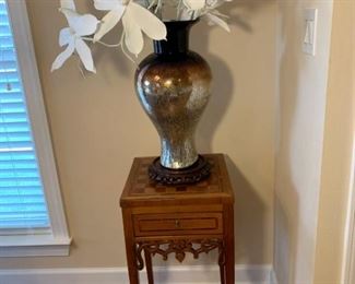Inlaid wood design Chess accent table and metallic colored vase and floral arrangement.