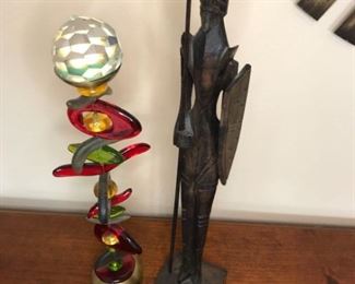 Art pieces. One is a glass stone art piece by Orna Lalo and the other is a hand carved wood folk art warrior statue.