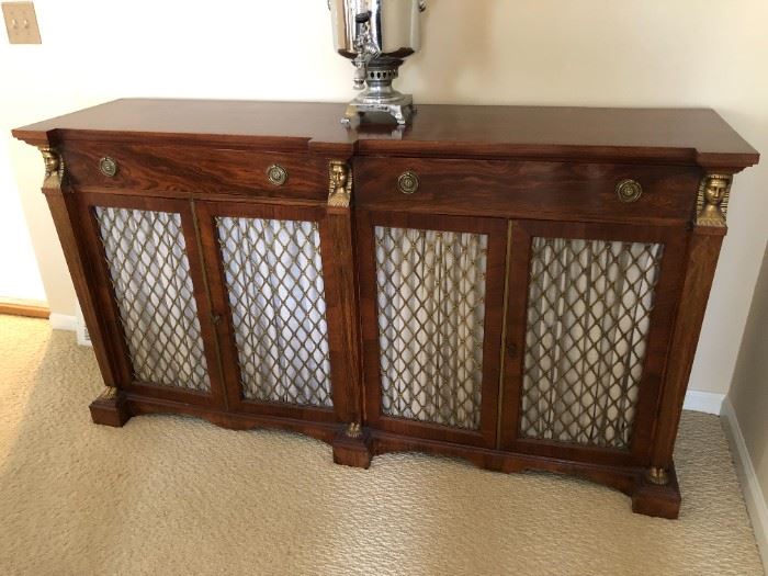 $800 Antique Regency Era mahogany sideboard with gilt bronze Sphinx masks and feet accents. Door panels are grill style with gilt rosettes and neutral color shirred fabric panels. There are shelves behind doors and 2 drawers for storage.
Perfect condition - No visible damage.