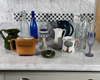 (12pc) LOT OF VESSELS | Group of various glass and pottery pitchers, cups, creamers, bottles, and swirly patterened champagne flute; tallest 12 in. 