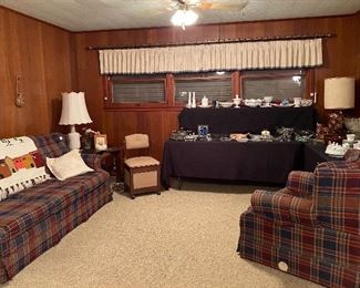 Plaid Sofa & Oversized Side Chair, Throw Pillows, Blanket, Goat with Plastic Cactus, End Table, Ceramic Lamp, Hand Carved Storage Container, Rock Maple End Table with Storage Area, Throw Rug, Sewing Machine Chair with Storage on Wheels, Assorted Collectibles