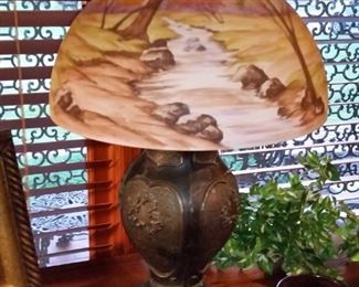 Bronze lamp has shade with forest stream scene