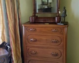Antique mahogany shaving mirror sitting atop a Lillian Russell walnut four drawer chest