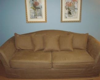 Lower Level: Here is a closeup of the RESTORATION HARDWARE sofa measuring 8 feet long. This sofa features a tight-back style with two detached seat cushions and five toss pillows and is sporting a light brown slipcover.  (Underneath is a white sofa.)
