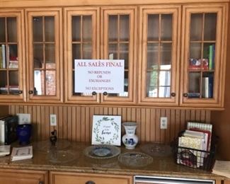 Kitchen:  Lots of cookbooks are displayed among several glass platters and miscellaneous items.