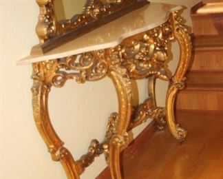 Large gold and gilt entry mirror with alabaster top on table.