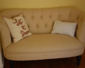 Deep buttoned loveseat with cream fabric.