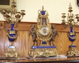 Italian Brevettato ornate clock with two candelabra. Embellished with metal and gilt sconces, blue enamel and cherubs.