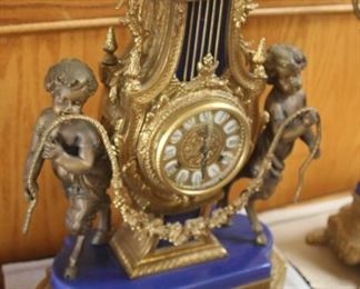 Italian Brevettato ornate clock with two candelabra. Embellished with metal and gilt sconces, blue enamel and cherubs.