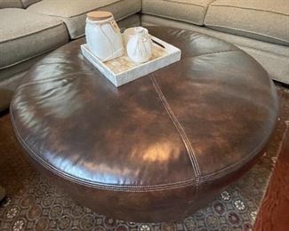 $750 - round leather ottoman with inlay welting trim with chestnut brown legs - 40” diameter x 17” h