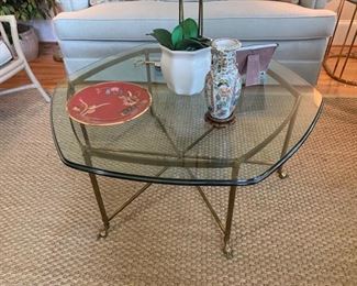 This is a thick glass topped table with a brass base featuring feet that are shaped like animal hooves. The glass is very thick and heavy and the brass is aged but very sturdy. 42x42x18 Glass thickness: 1 inch. Items on table not included. https://ctbids.com/#!/description/share/949920