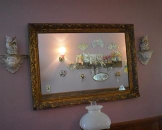 Beautiful Gold Framed Wall Mirror in Rococo plus matching Cherub wall shelves and Porcelain figurines. Notice the Collectible Cards, Fans, and other items in the Mirrors reflection.