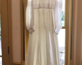 This beautiful wedding dress is made of satin and two shades of lace. The dress features a high neck collar with lace detail along the top of dress and the sleeves as well. Dress appears to be a size 10-12.  Dress was handmade by client in 1975. https://ctbids.com/#!/description/share/953548