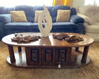 Beautiful wooden coffee table with decorative items atop it, including rooster wall hangings and a swan sculpture.