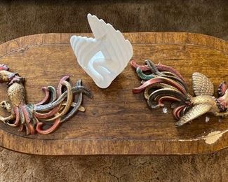 Top view of a beautiful wooden coffee table, with decorative items atop it. Decorative items include rooster wall hangings and a swan sculpture.