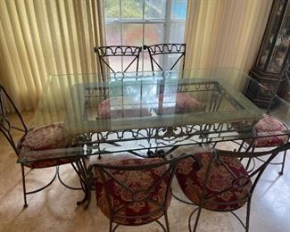 Glass top dining table with six chairs and cushions. 