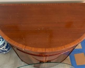 Beautiful antique/vintage demilune half moon cabinet with custom glass top. In great condition with one knick on trim and some wear/scratches on feet. Measures 38" wide, 19.5" deep and 33" tall. 