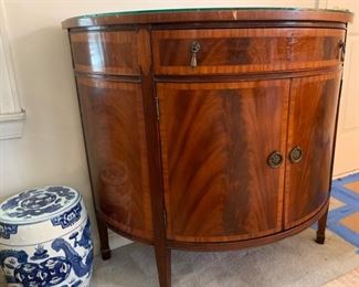 Beautiful antique/vintage demilune half moon cabinet with custom glass top. In great condition with one knick on trim and some wear/scratches on feet. Measures 38" wide, 19.5" deep and 33" tall. 