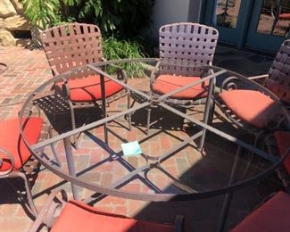 5’ (60”) glass top table and 8 chairs (fabric strap backs). Weathered but in good condition, includes umbrella. $385